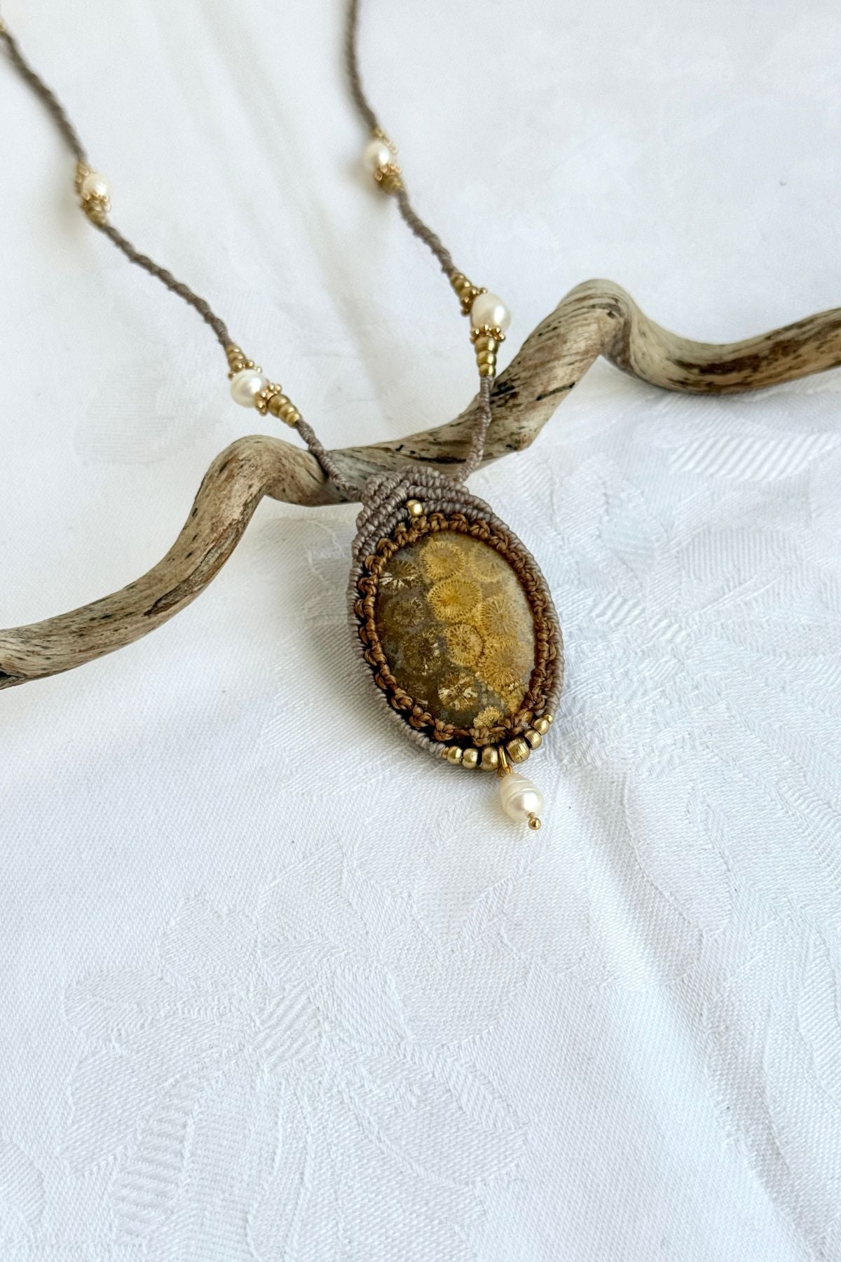 Close-up of side detail of fossil coral pendant necklace with freshwater pearls and organic texture of coral fossil