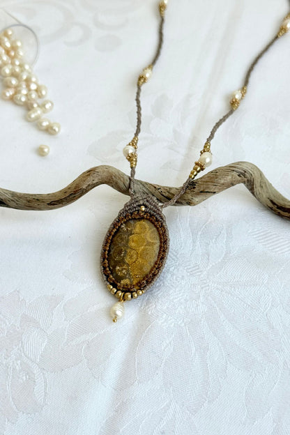Close-up of opposite side of fossil coral pendant necklace highlighting pearl placement and sculptural macramé design