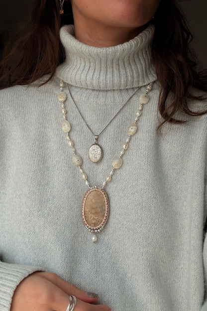 Model styling the fossil coral statement necklace, a luxury ocean inspired jewelry, adorned with elegant pearls.