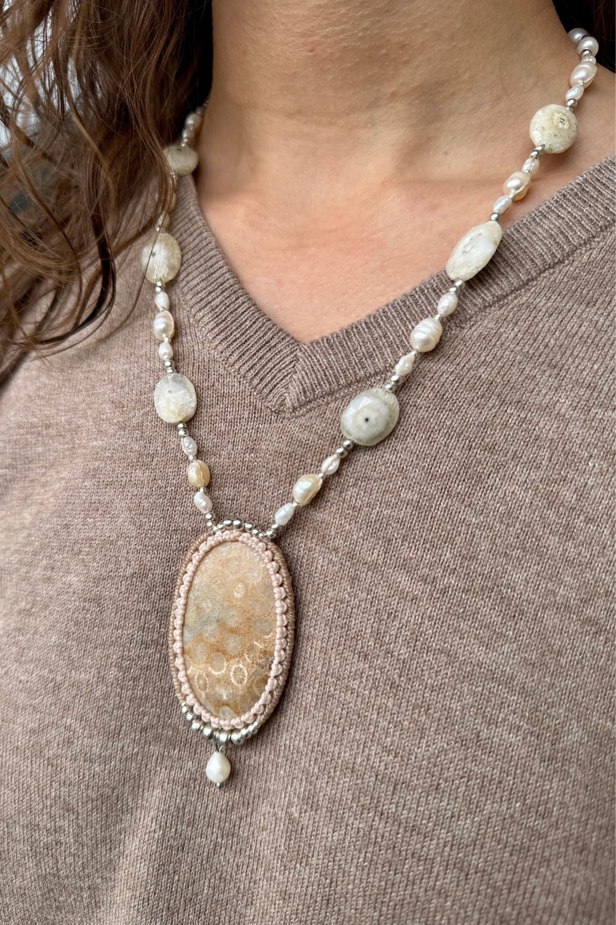 Model wearing a fossil coral statement necklace, adorned with elegant pearls and Solar Agate gemstone.