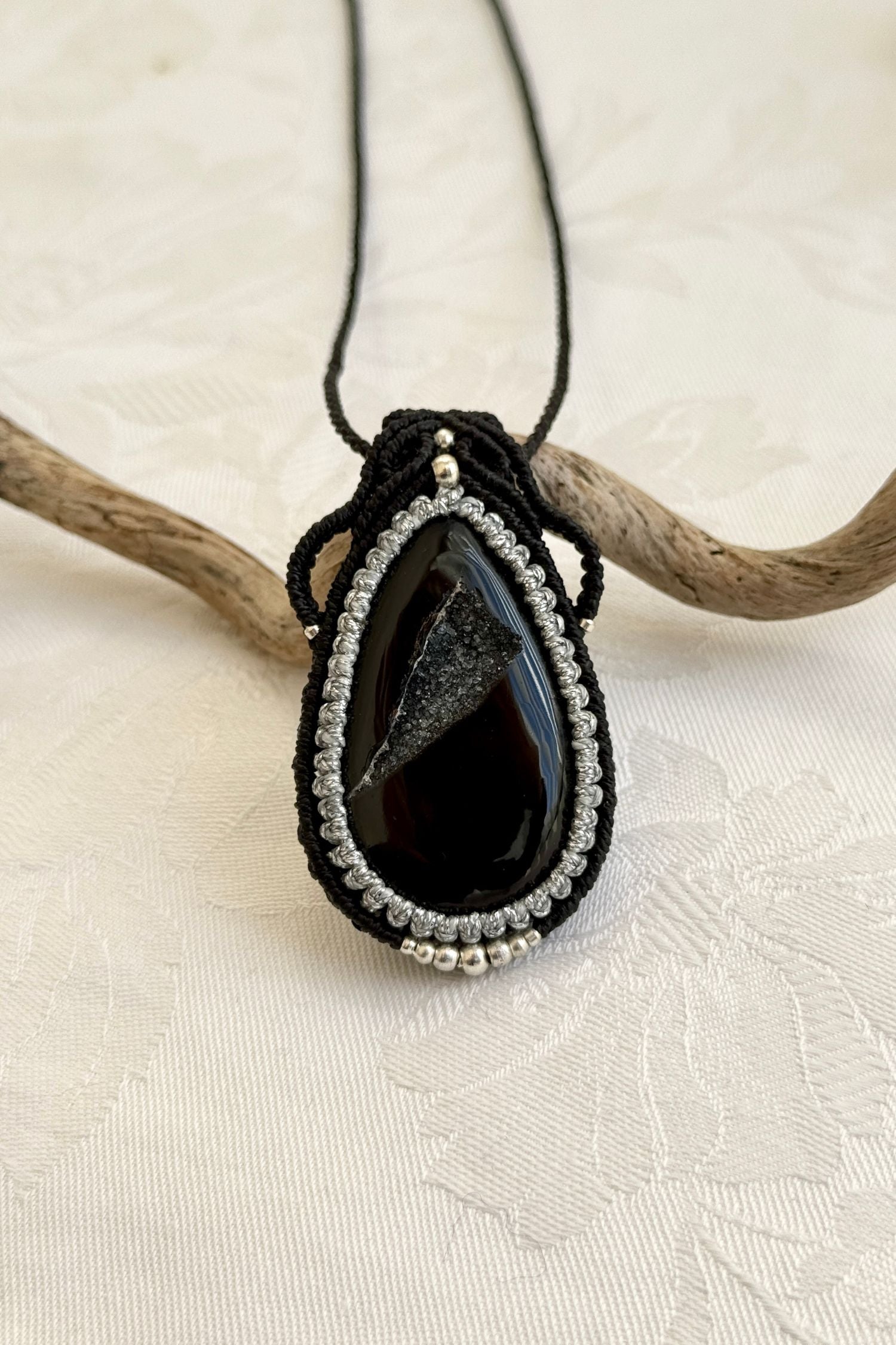 Detailed close-up of Druzy Onyx gemstone in a handmade macrame necklace. Showcasing natural textures and gemstone glow.