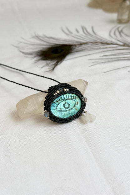 One-of-a-kind Labradorite necklace with carved protective eye, laid flat to highlight its unique shimmer and design.