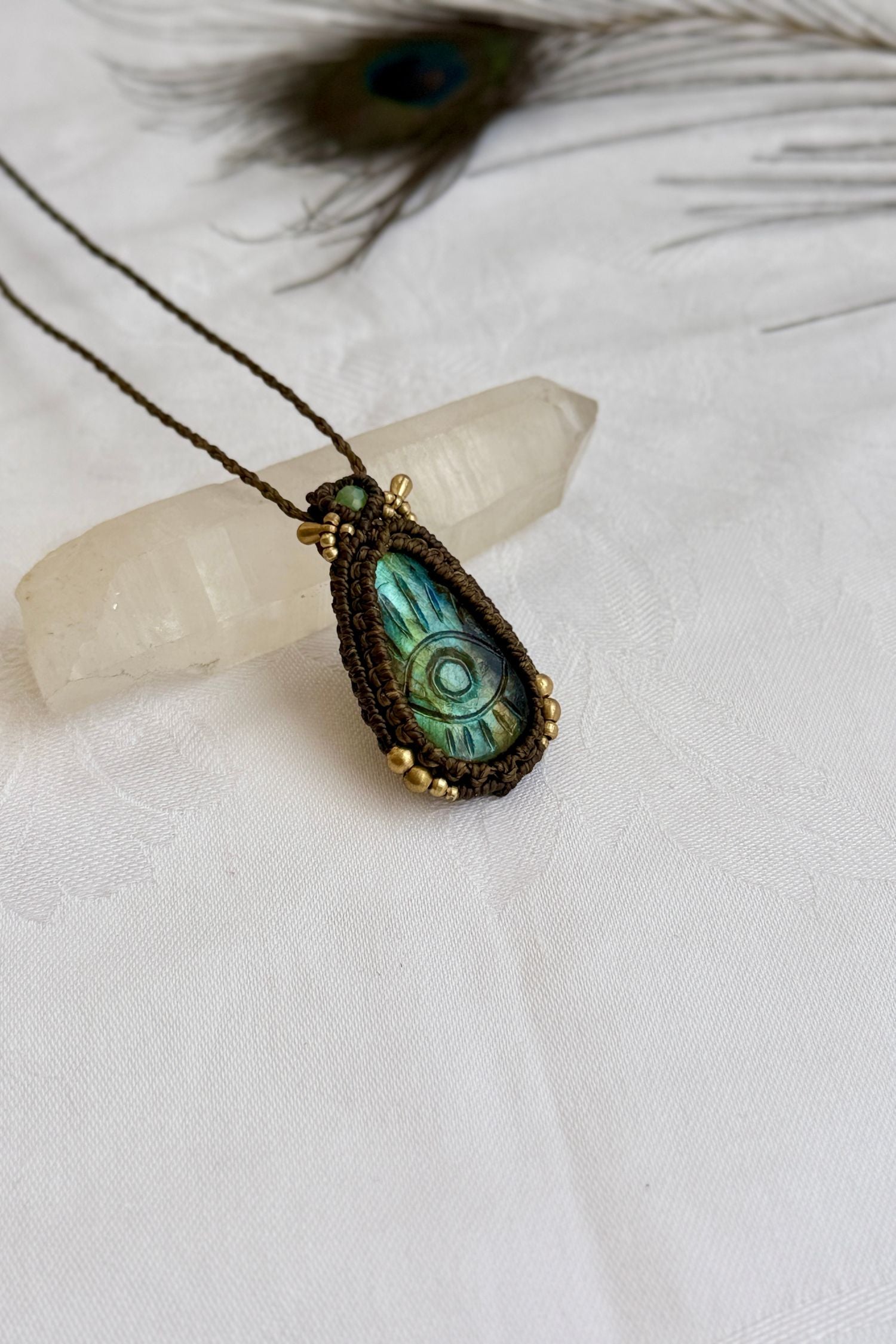 One-of-a-kind Labradorite necklace with carved protective eye, laid flat to highlight its unique shimmer and design.