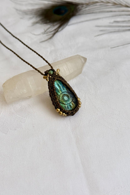 One-of-a-kind Labradorite necklace with carved protective eye, laid flat to highlight its unique shimmer and design.