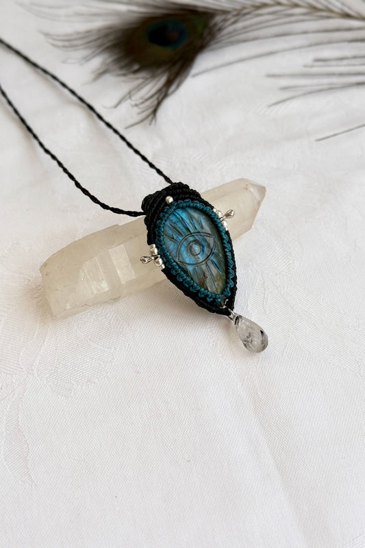 Handmade Labradorite macrame necklace with carved protective eye design, laid flat to show gemstone details and craftsmanship.
