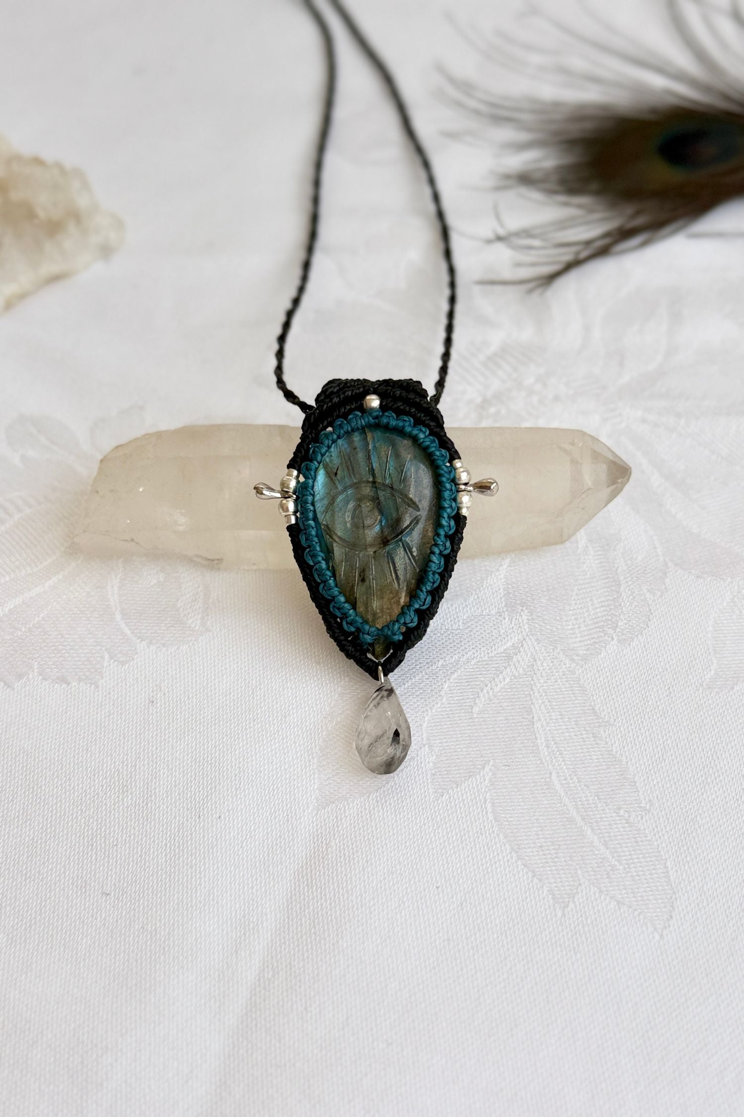 One-of-a-kind Labradorite necklace with carved protective eye, laid flat to highlight its unique shimmer and design.