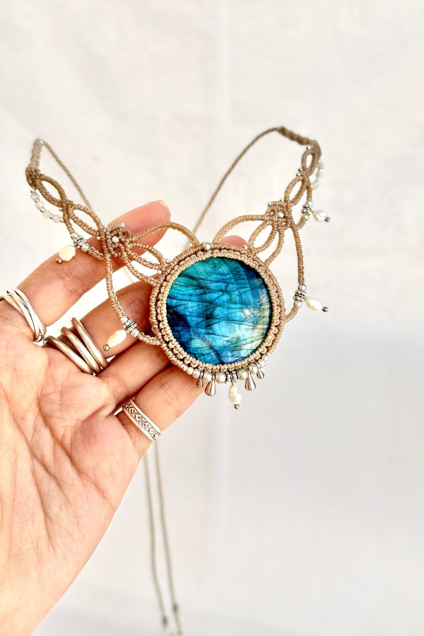 Close-up of a handmade Labradorite macramé necklace showing vibrant blue flash, pearl accents, and intricate detailing.