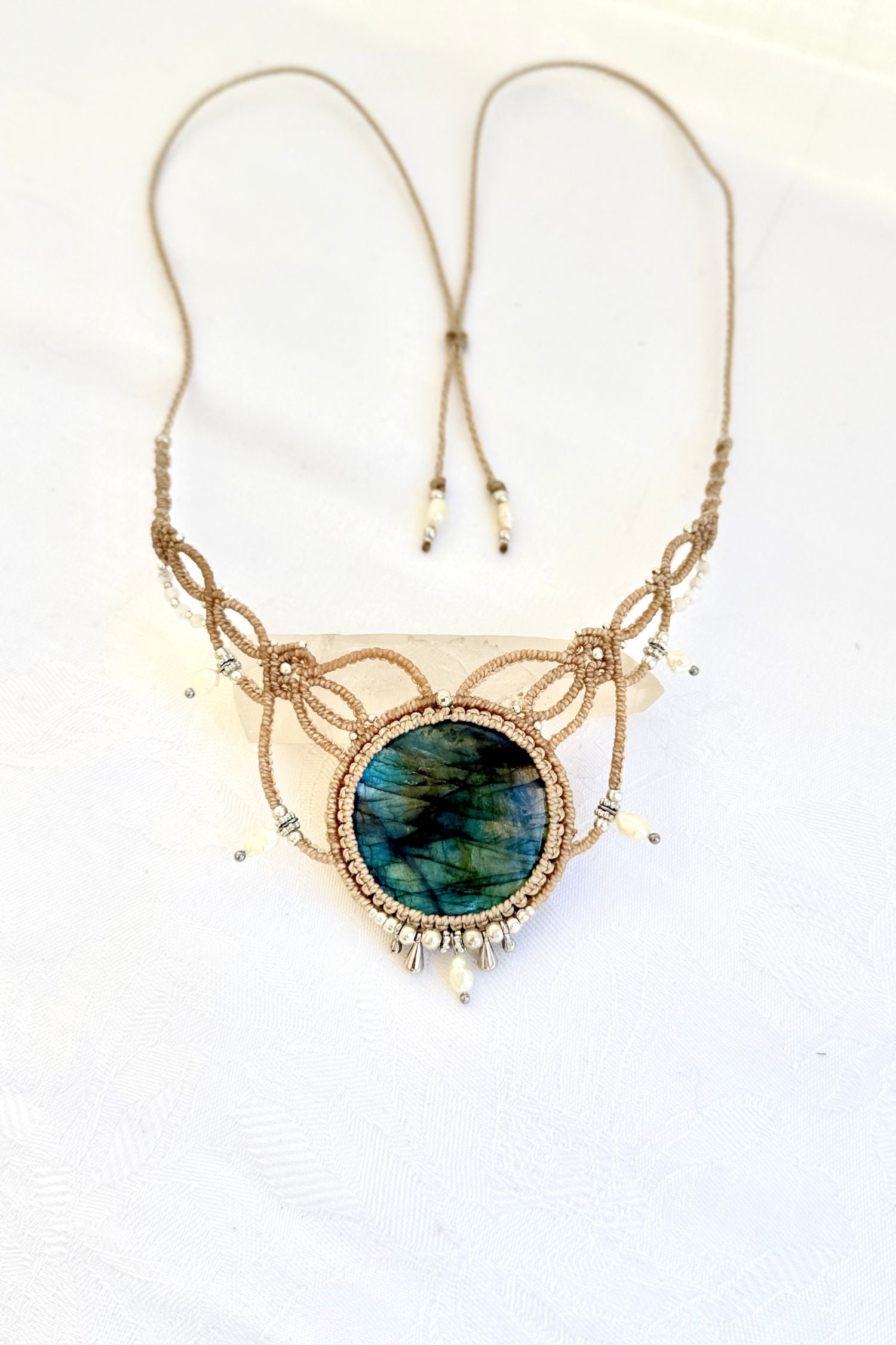 Handmade Labradorite macramé necklace laid flat, featuring freshwater pearl drops, silver beads, and adjustable ends.