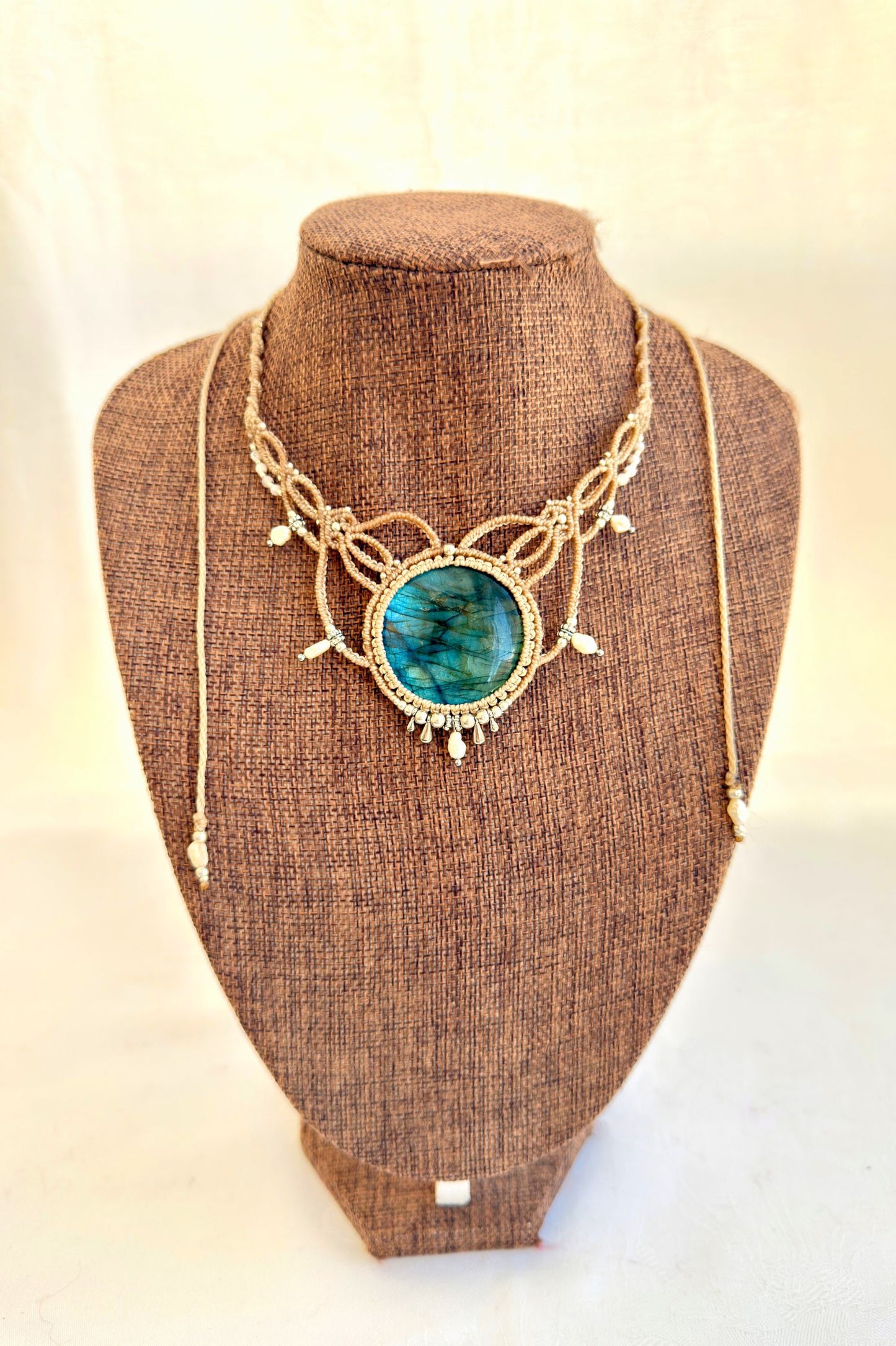 Labradorite macramé necklace displayed on bust, featuring deep blue gemstone and elegant pearl details.
