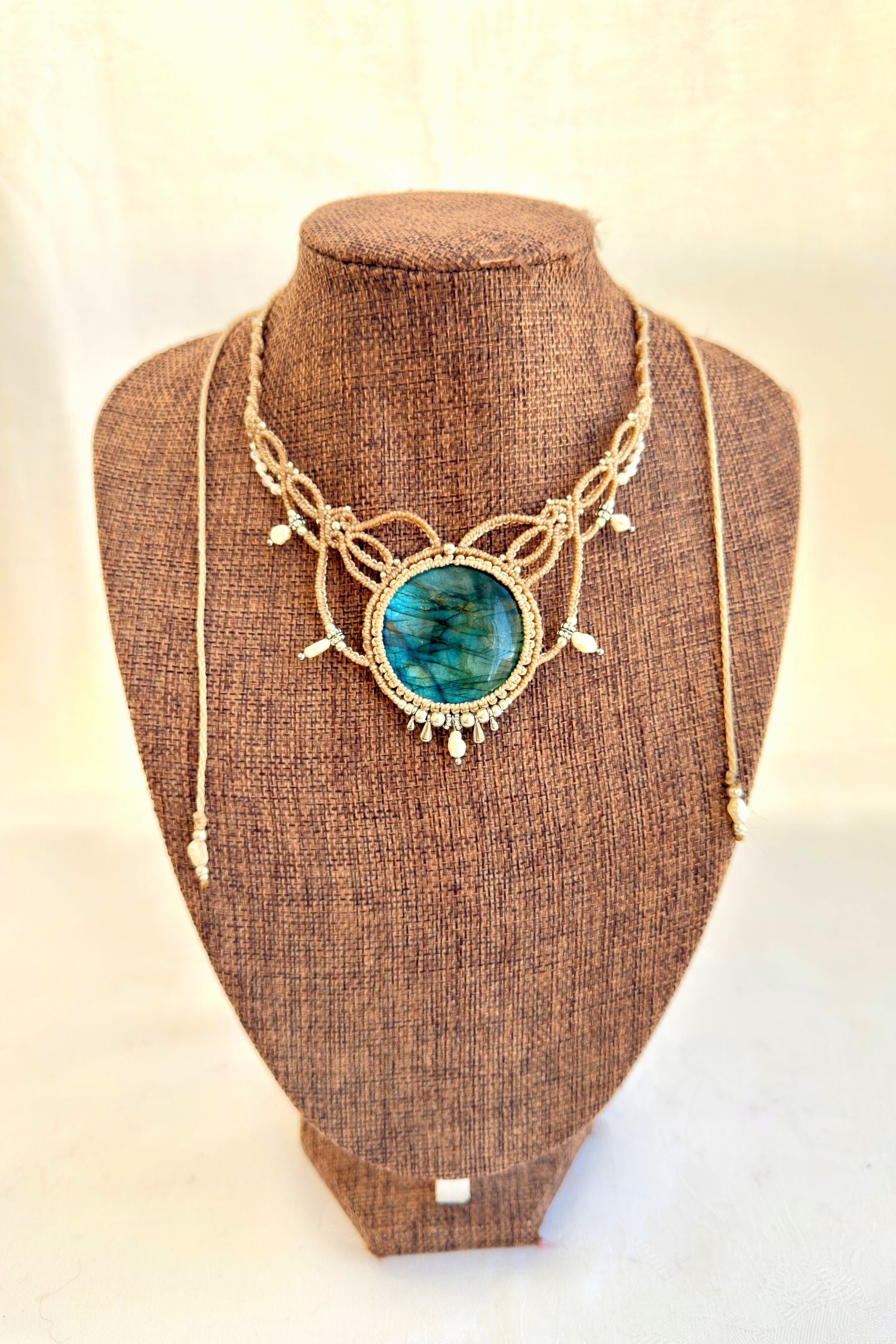 Labradorite macramé necklace displayed on bust, featuring deep blue gemstone and elegant pearl details.