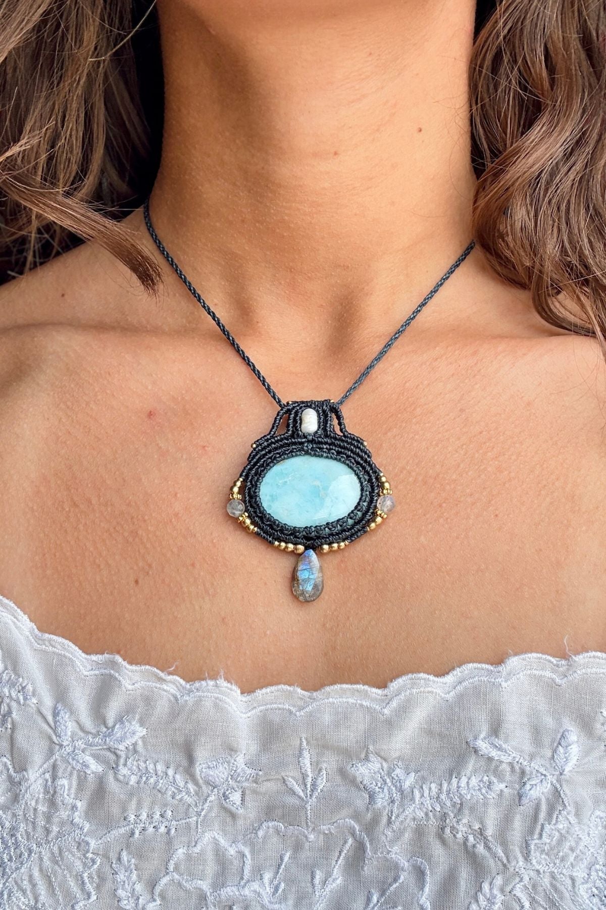 Larimar and Labradorite macrame necklace worn with a white top, showing how the pendant sits on the chest.