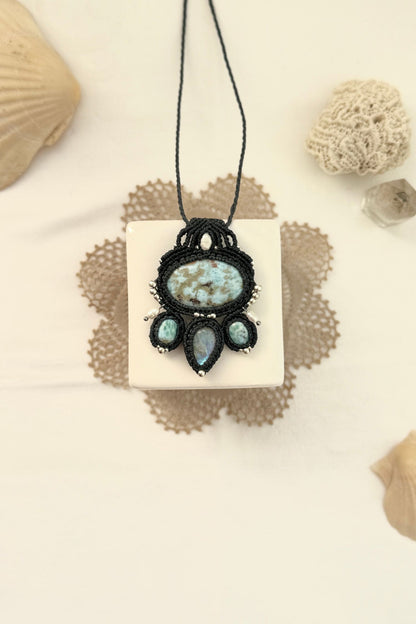 One of a kind Larimar and Moonstone macramé necklace laid flat, featuring freshwater pearls, silver details, and navy blue cord