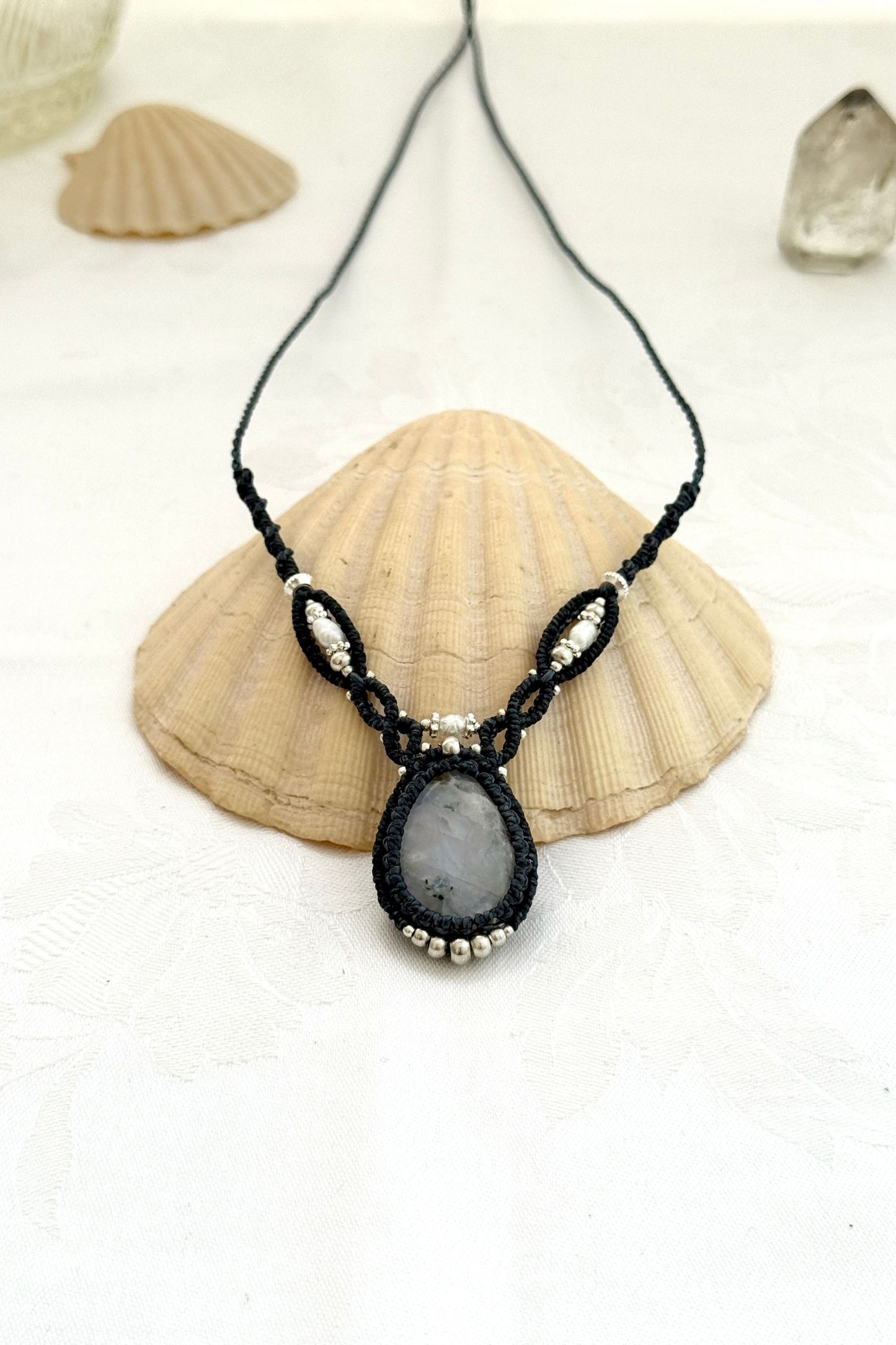 Close-up of a one of a kind Moonstone V-shaped macramé necklace showing the shine of the gemstone, Freshwater Pearl and silver details
