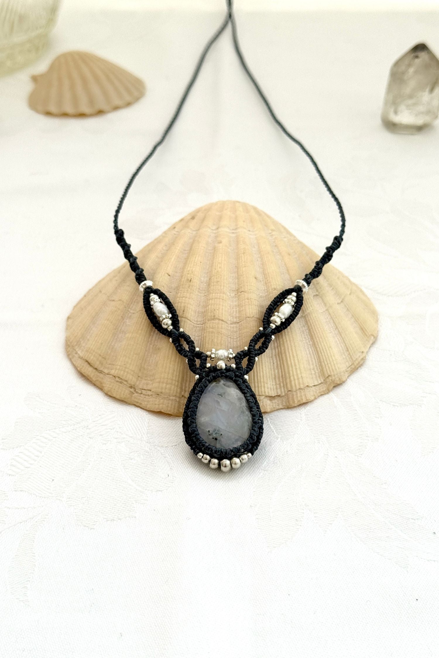 Close-up of a one of a kind Moonstone V-shaped macramé necklace showing the shine of the gemstone, Freshwater Pearl and silver details