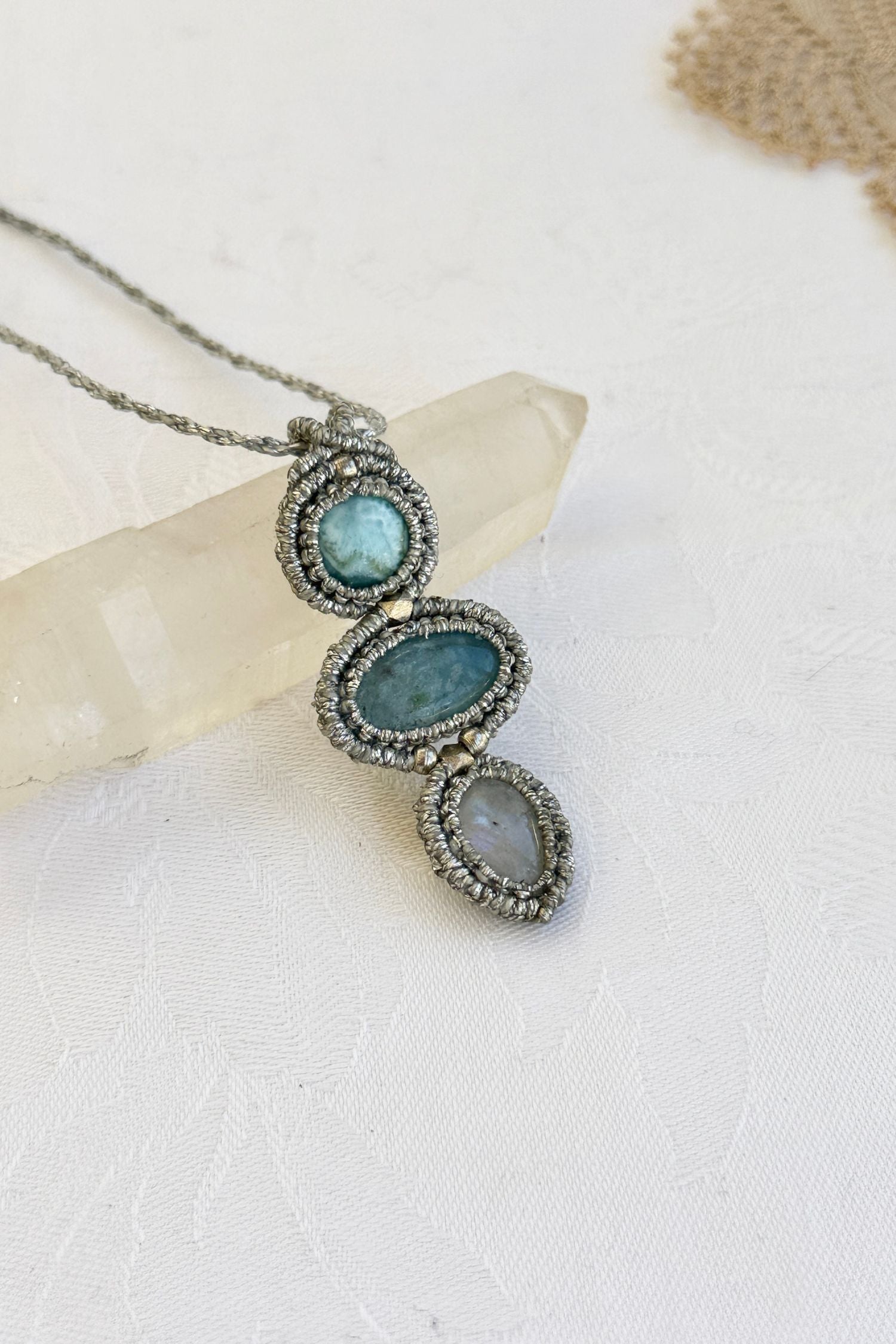 Close-up of the Larimar, Aquamarine and Moonstone macrame necklace in a unique setting. Highlighting the craftsmanship and gemstones details.