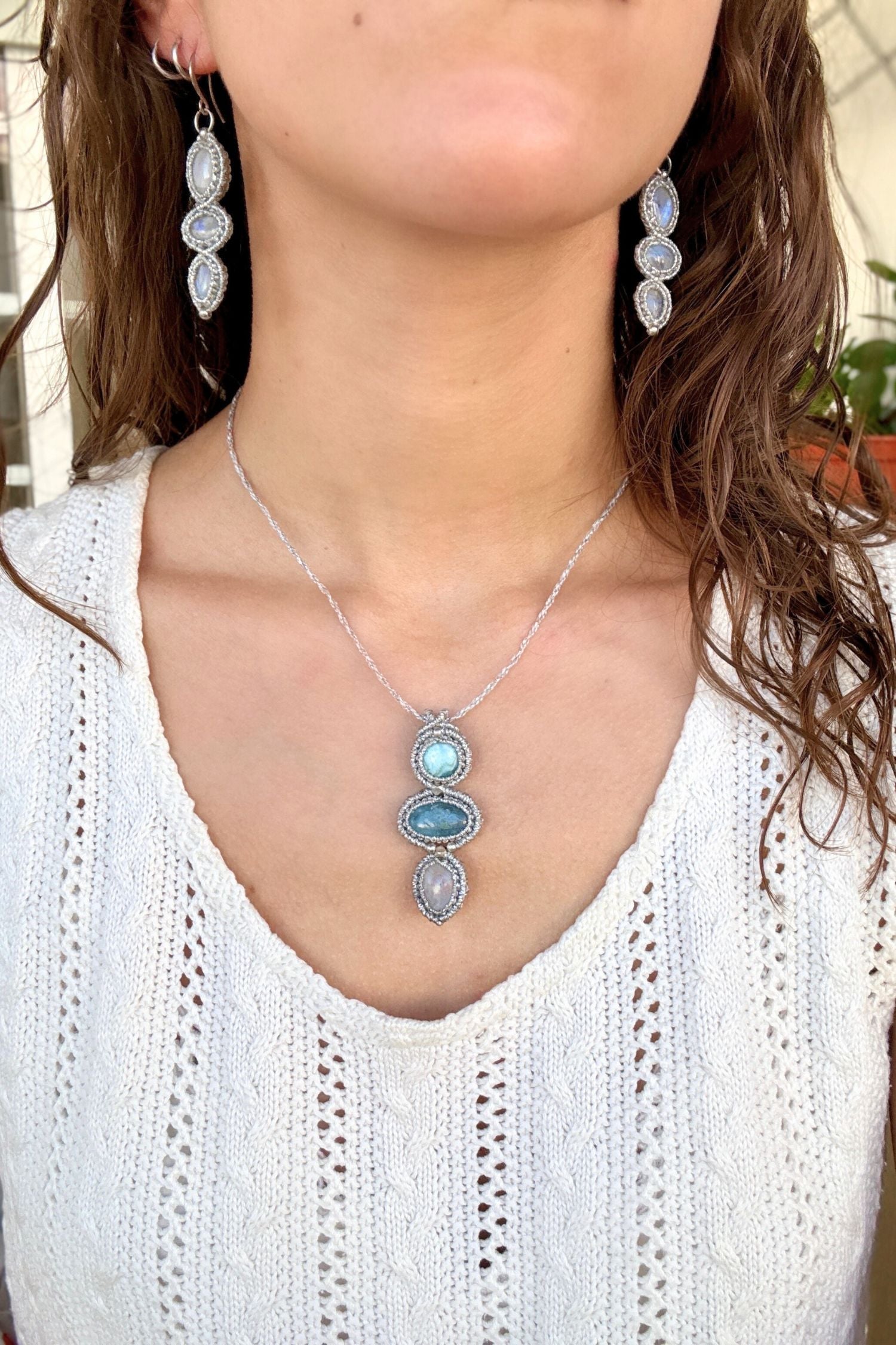 Larimar, Aquamarine and Moonstone macrame necklace worn by a model. Showcasing the unique handmade design and how it looks when worn.
