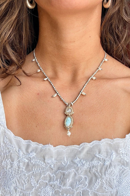 Moonstone and Larimar necklace worn with a white embroidered top, showing how the pendant sits below the collarbones.