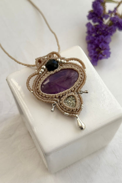 Detailed close-up of Amethyst and Raw Druzy Pyrite gemstones in a handmade macrame necklace. Showcasing natural textures and gemstone glow.