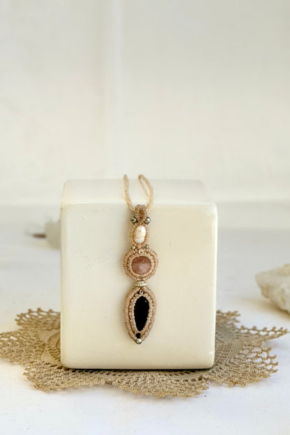 Detailed close-up of Freshwater Pearl, Rose Quartz and Amethyst gemstones in a handmade macrame necklace. Showcasing natural textures and gemstone glow.