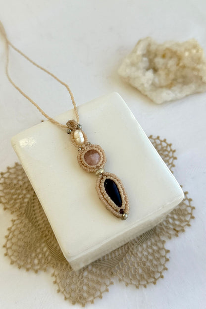 Close-up of the Freshwater Pearl, Rose Quartz and Amethyst macrame necklace in a unique setting. Highlighting the craftsmanship and gemstones details.