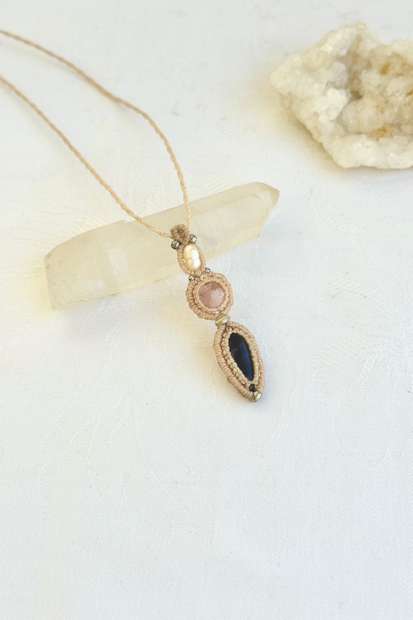 Side-angle view of the handmade macrame necklace with Freshwater Pearl, Rose Quartz and Amethyst. Showcasing depth, knotting details, and stone textures.