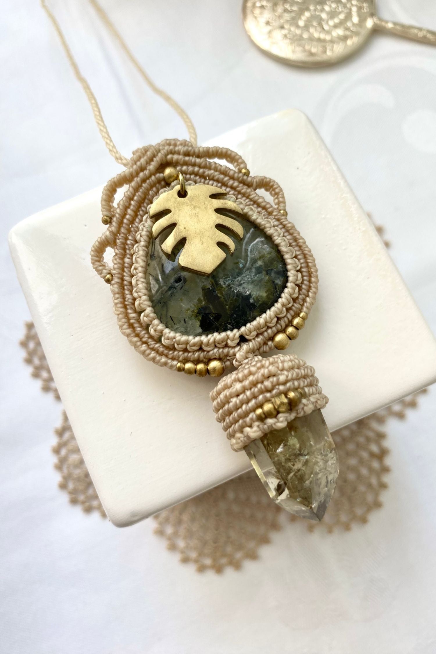 Artistic jewelry display of a one-of-a-kind macrame necklace, featuring hand-selected gemstones in a timeless and elegant design.