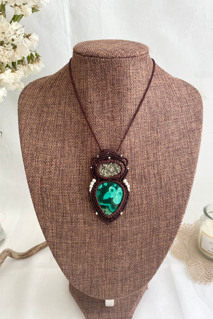 Handmade macrame necklace featuring malachite and raw pyrite displayed on a necklace stand, giving an overview of the piece’s size and design.