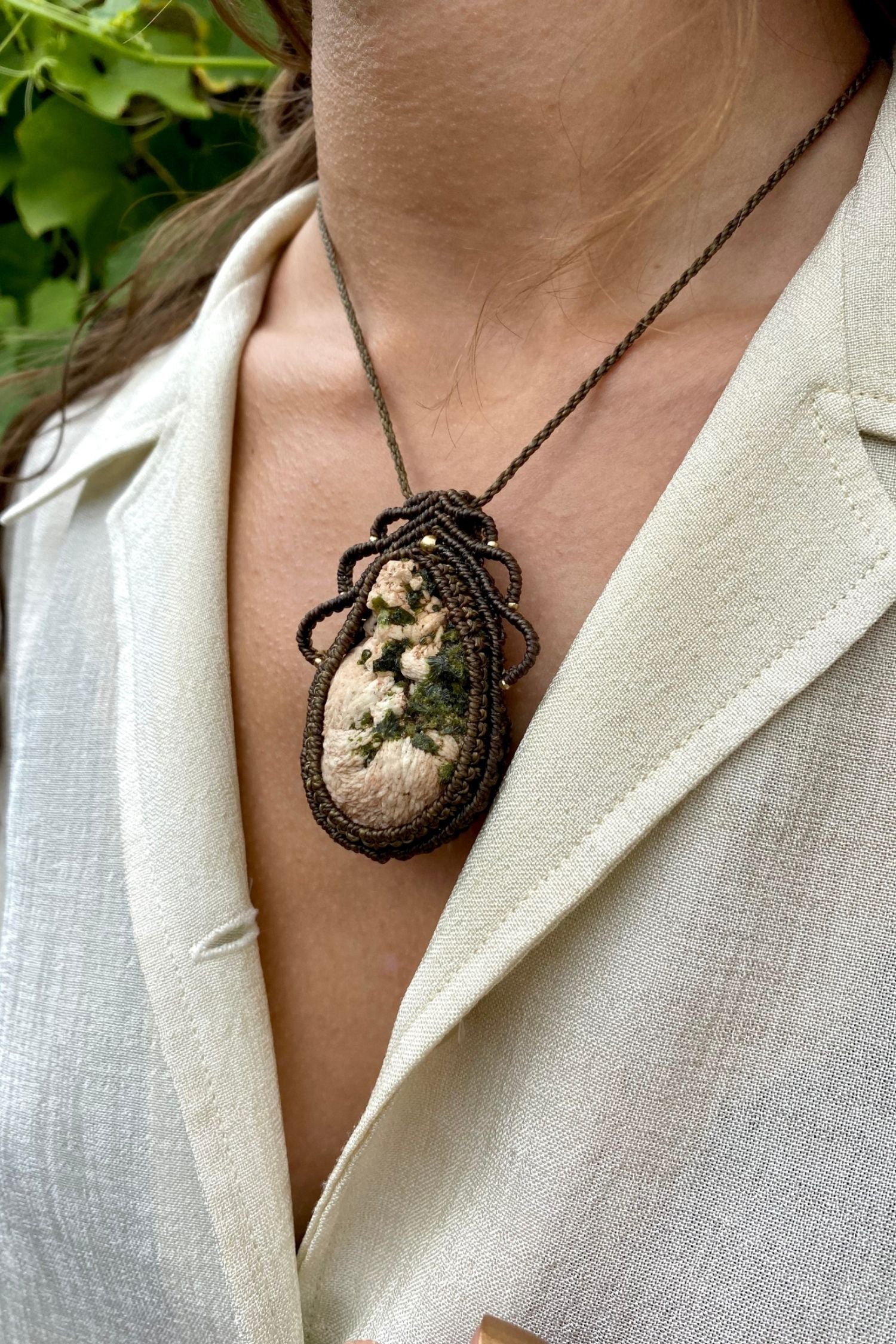 Artistic jewelry display of a one-of-a-kind macrame necklace, featuring hand-selected gemstones in a timeless and elegant design.