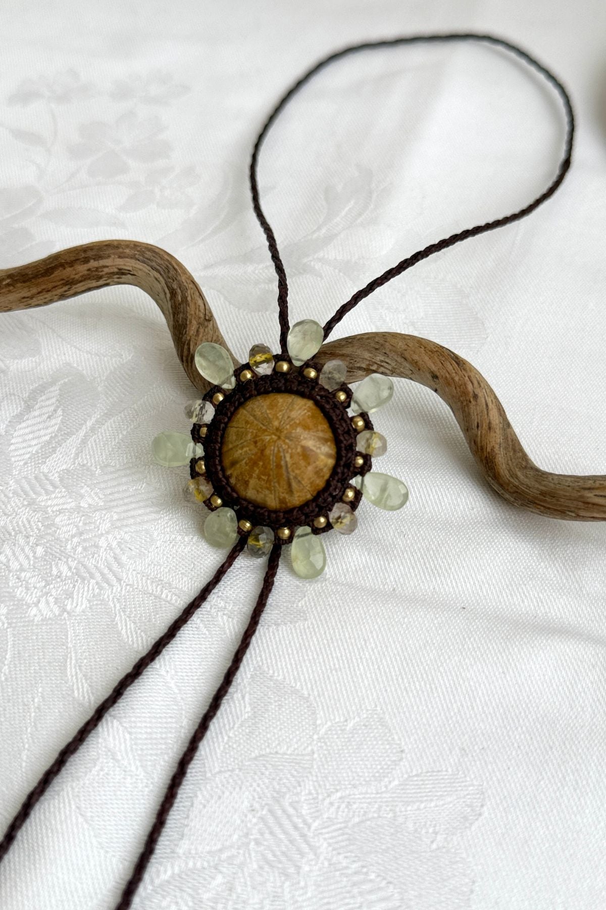 Close-up of fossilized sea urchin centerpiece with radiating peridot and rutilated quartz accents