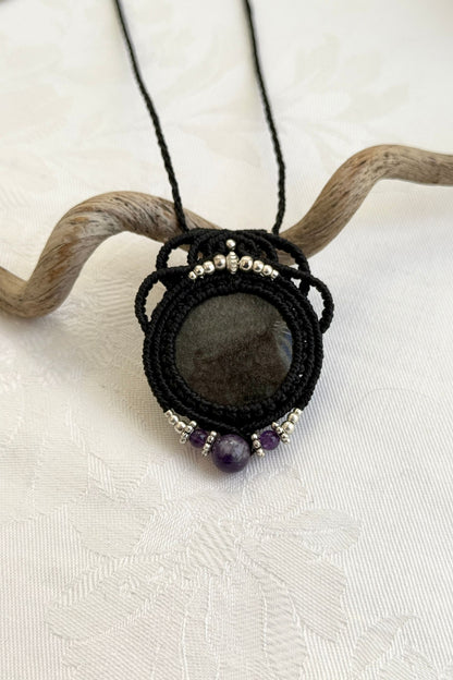 Close-up of the Silver Sheen Obsidian and Amethyst macrame necklace in a unique setting. Highlighting the craftsmanship and gemstones details.