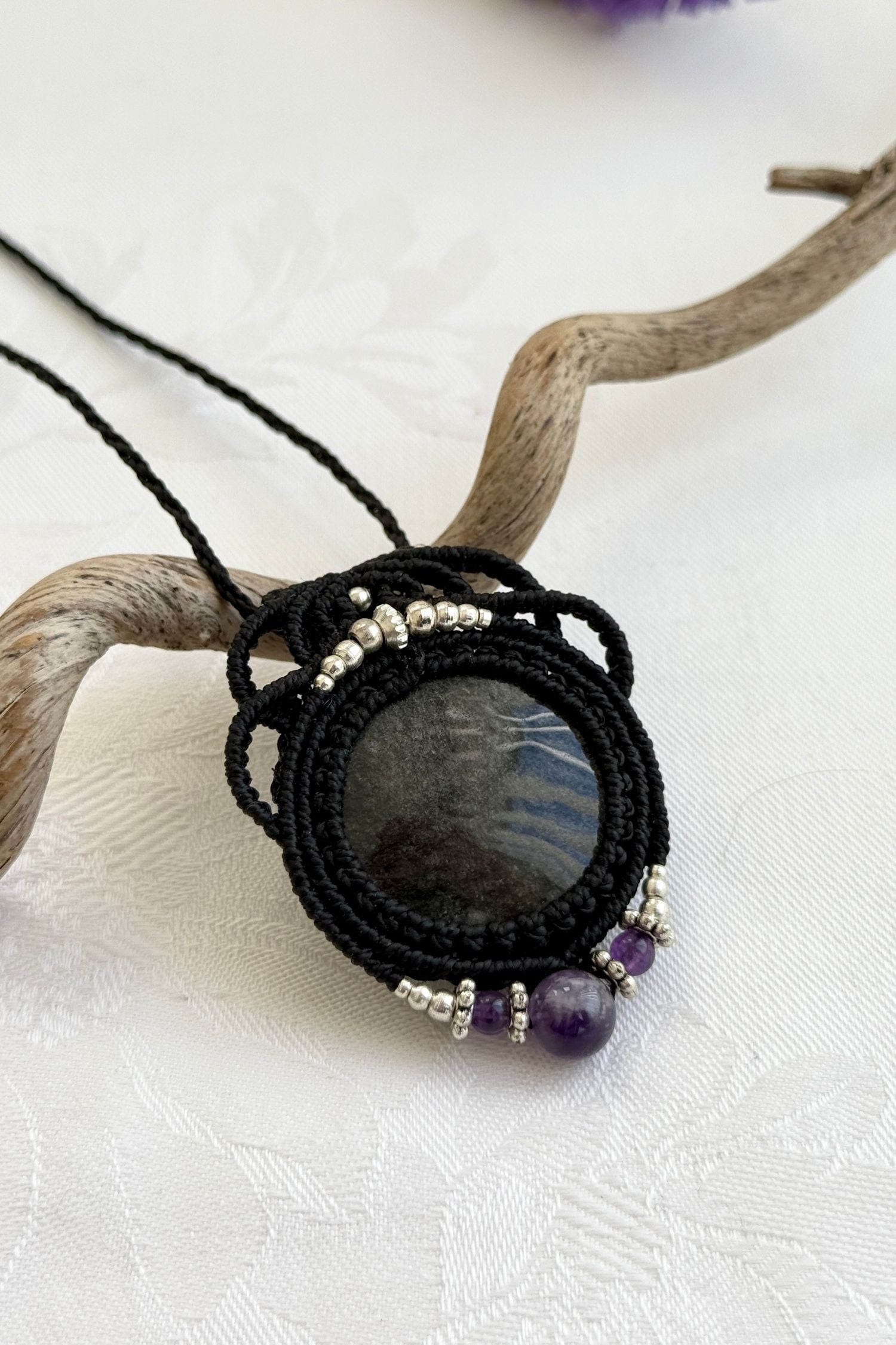 Side-angle view of the handmade macrame necklace with Silver Sheen Obsidian and Amethyst. Showcasing depth, knotting details, and stone textures.