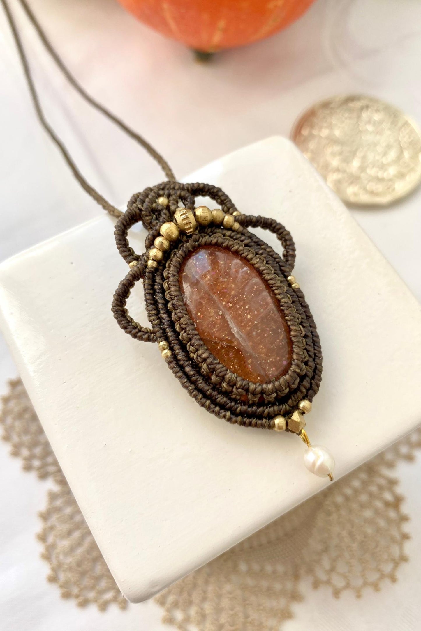 Artistic jewelry display of a one-of-a-kind macrame necklace, featuring hand-selected gemstones in a timeless and elegant design.