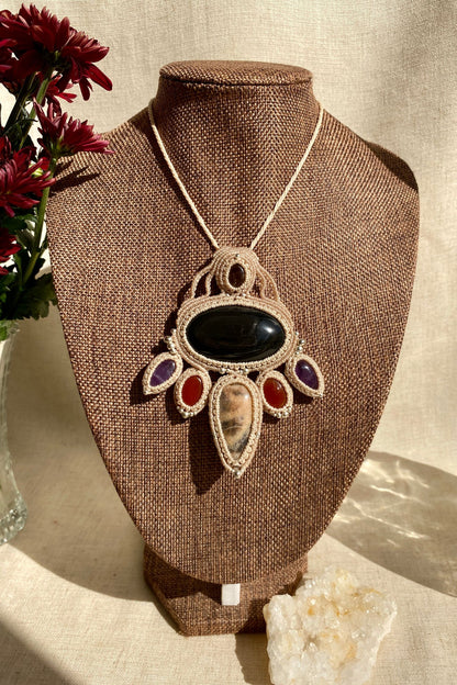 Handmade macrame necklace featuring obsidian, black moonstone, smoky quartz, carnelian, and amethyst, displayed on a necklace stand to show how it drapes.