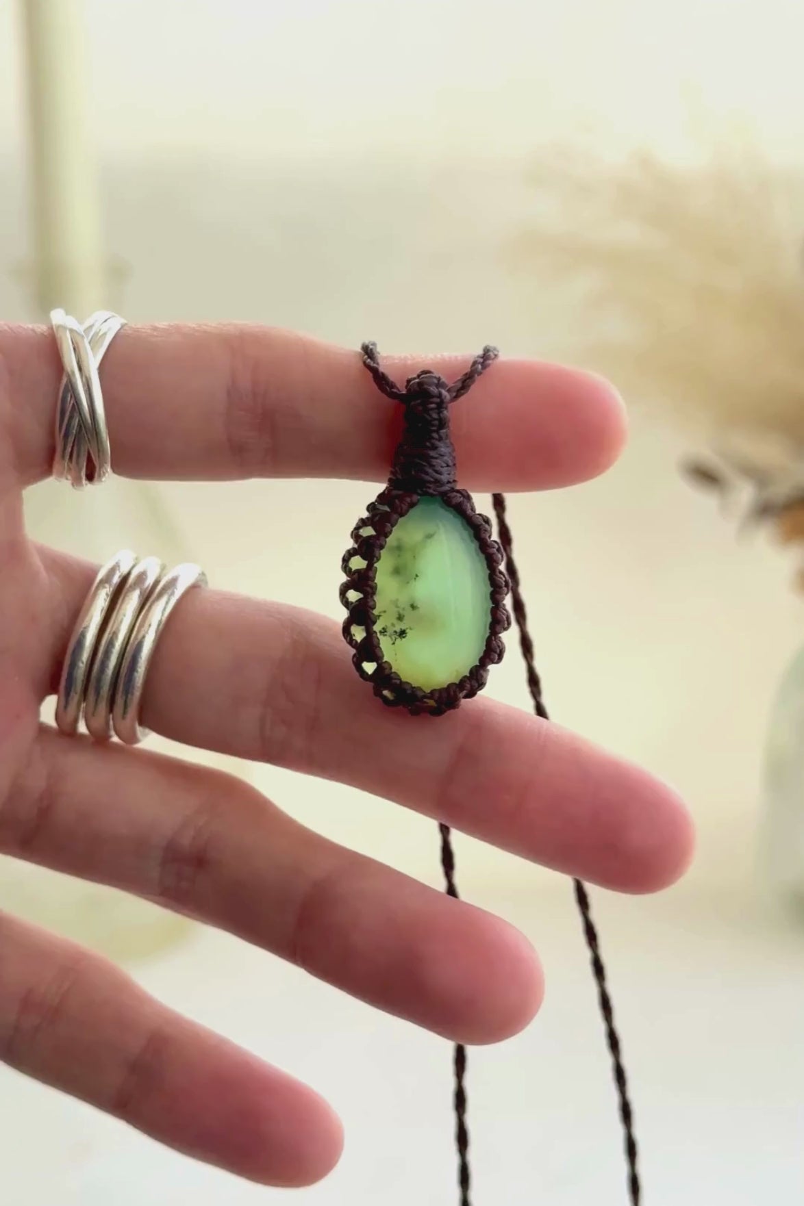 Video showcasing the harmonious vibrant green, semi-translucent Chrysoprase gemstone, held in hand with its brown macrame necklace.