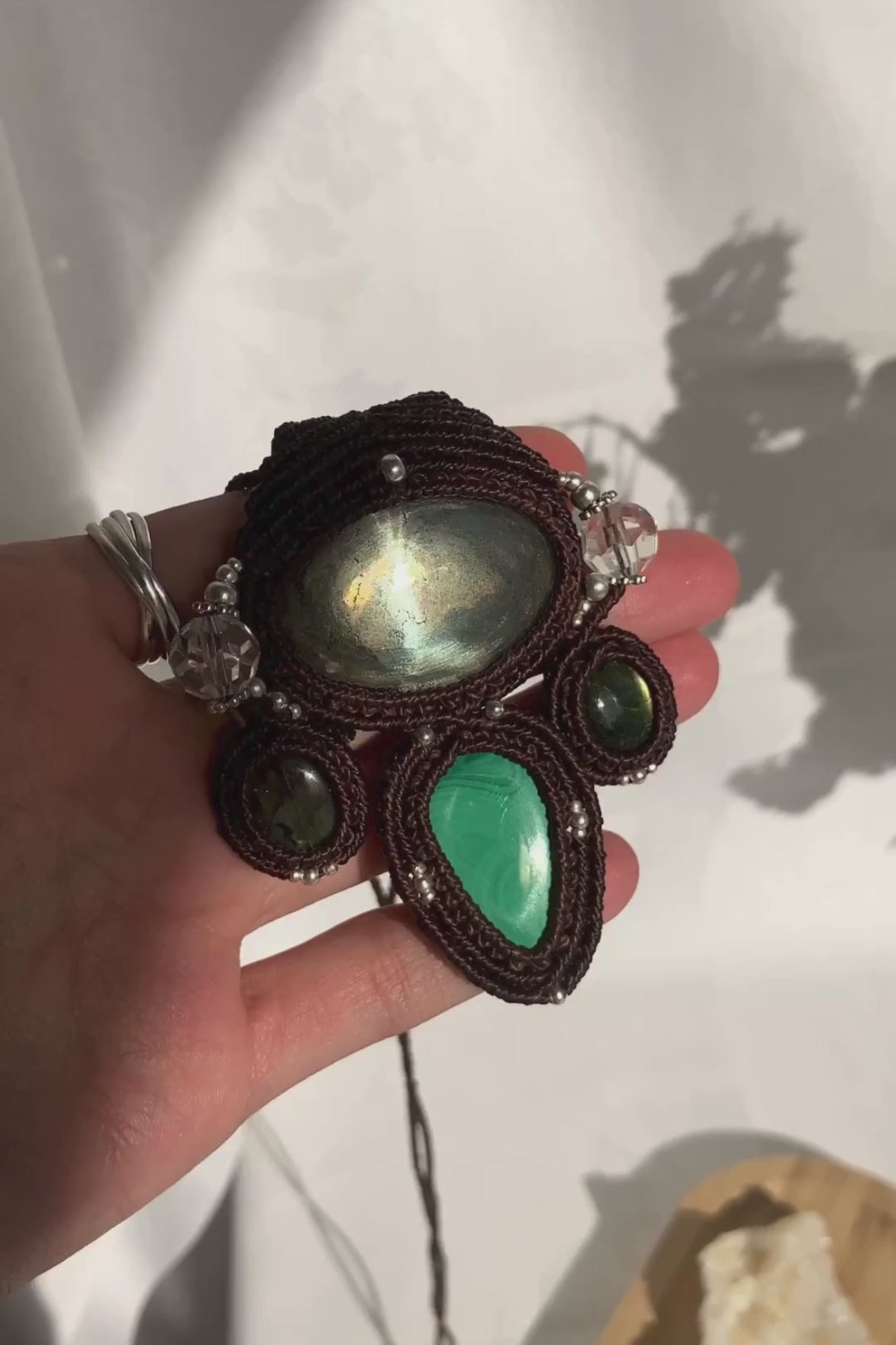 Close-up video of a handmade gemstone necklace, capturing the natural shine and intricate details of Pyrite, Labradorite, Malachite and Quartz beads. The unique design and polished gemstones reflect the light beautifully, highlighting the craftsmanship and one-of-a-kind artistry.