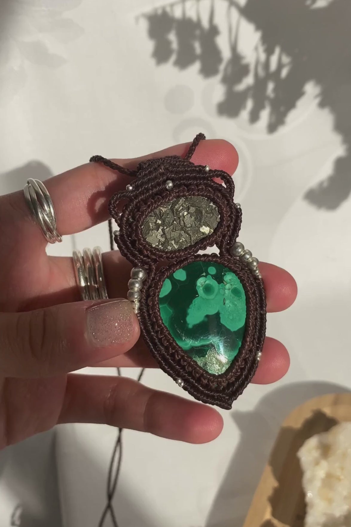 Video showcasing handmade macrame necklace with malachite and raw pyrite, highlighting the gemstone’s shine and movement.