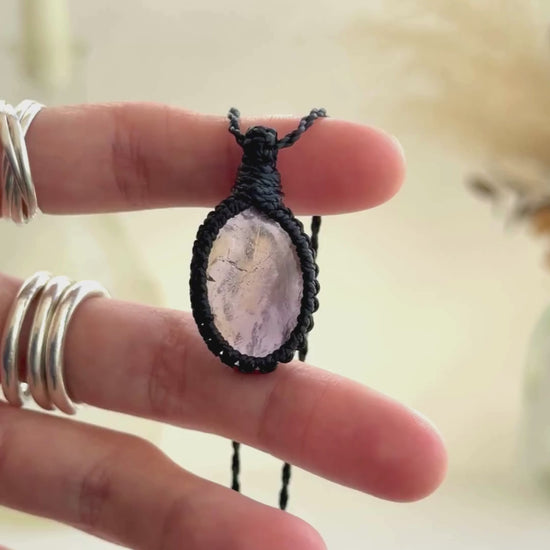 Video showcasing the harmonious blend of soft purple Amethyst hues and the mysterious golden glow of Citrineo gemstones, held in hand with its black macrame necklace.