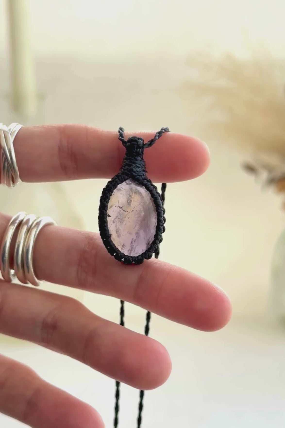 Video showcasing the harmonious blend of soft purple Amethyst hues and the mysterious golden glow of Citrineo gemstones, held in hand with its black macrame necklace.