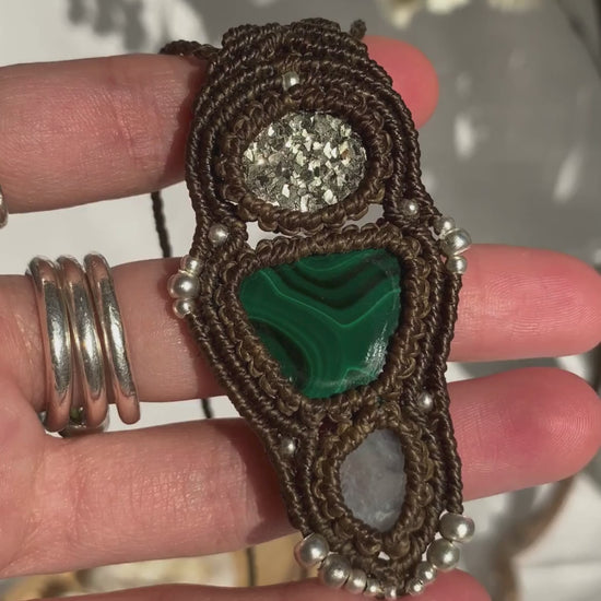 Close-up video of a handmade gemstone necklace, capturing the natural shine and intricate details of Raw Pyrite, Moonstone and Malachite. The unique design and polished gemstones reflect the light beautifully, highlighting the craftsmanship and one-of-a-kind artistry.