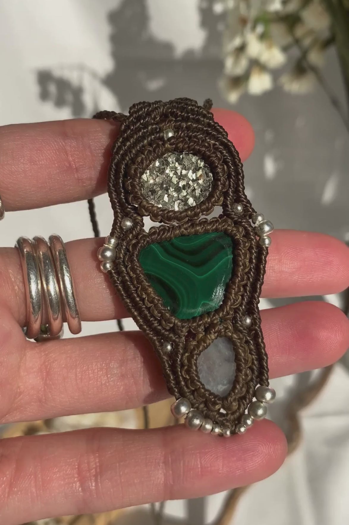 Close-up video of a handmade gemstone necklace, capturing the natural shine and intricate details of Raw Pyrite, Moonstone and Malachite. The unique design and polished gemstones reflect the light beautifully, highlighting the craftsmanship and one-of-a-kind artistry.