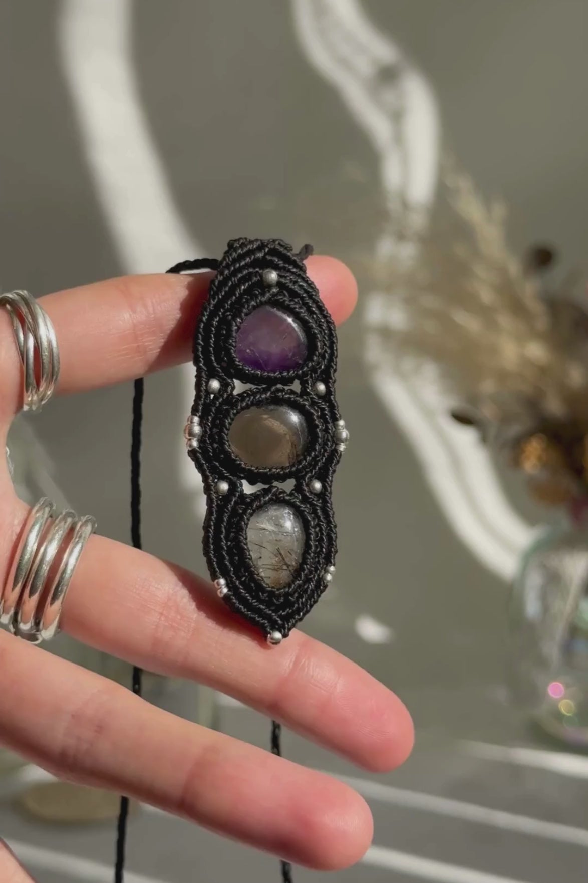 Video of a handmade Amethyst, Smoky Quartz and Tourmaline Quartz macrame necklace. Displaying natural gemstone colors, light reflections, and fine macrame details.