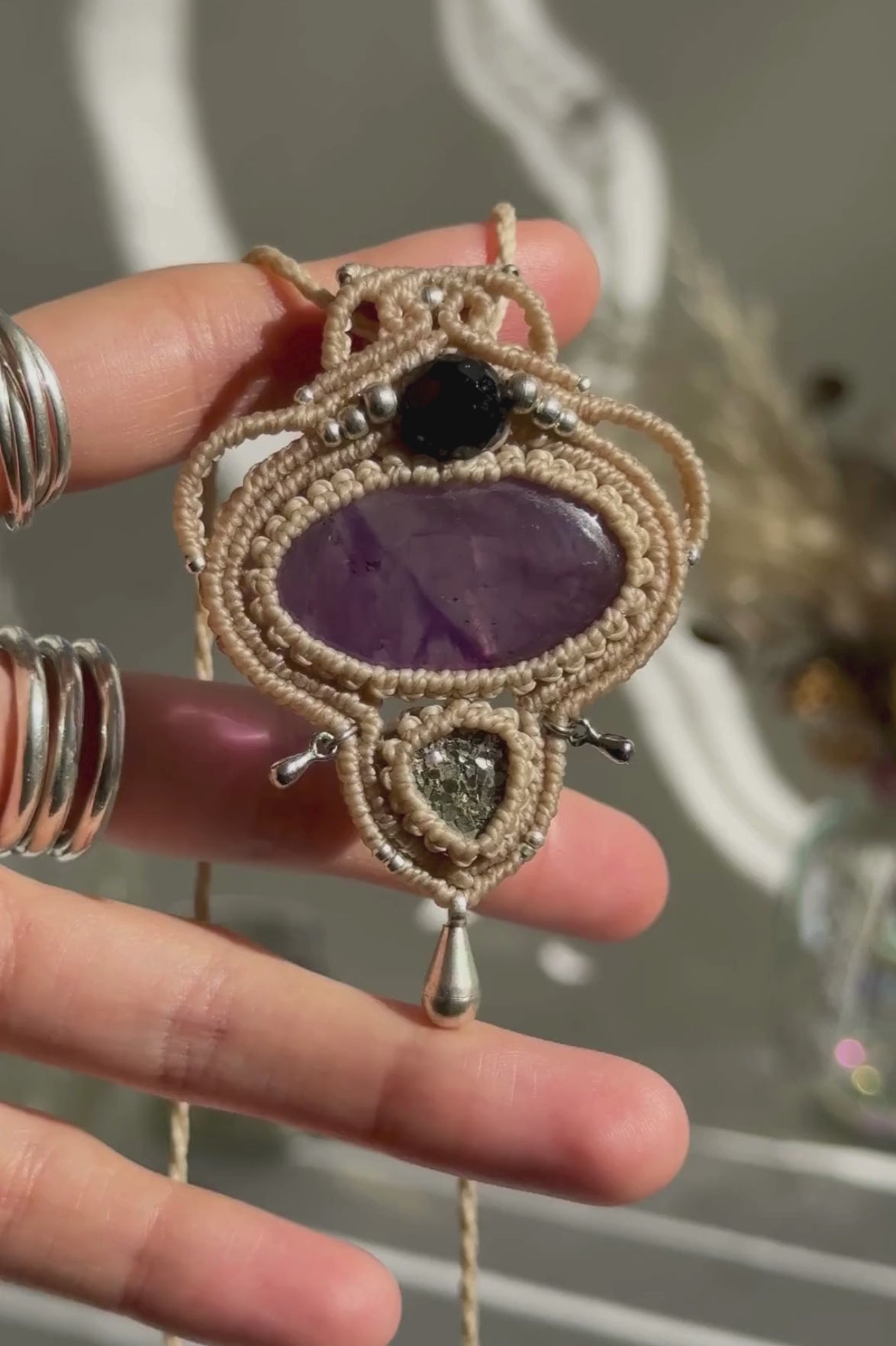 Video of a handmade Amethyst and Raw Druzy Pyrite macrame necklace. Displaying natural gemstone colors, light reflections, and fine macrame details.