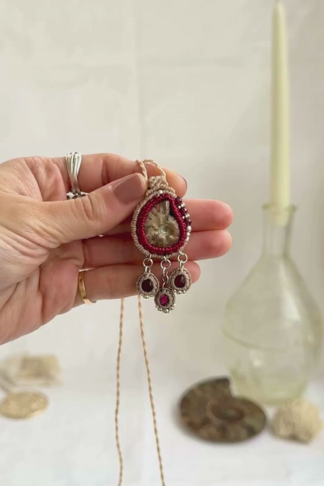 Ammonite fossil necklace with dangling garnet drops, highlighting iridescence and gemstone sparkle