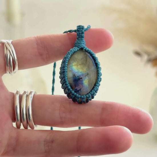 Video showcasing the harmonious deep blue flashes and subtle golden highlights of the Labradorite gemstone, held in hand with its blue macrame necklace.