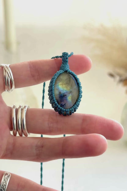 Video showcasing the harmonious deep blue flashes and subtle golden highlights of the Labradorite gemstone, held in hand with its blue macrame necklace.