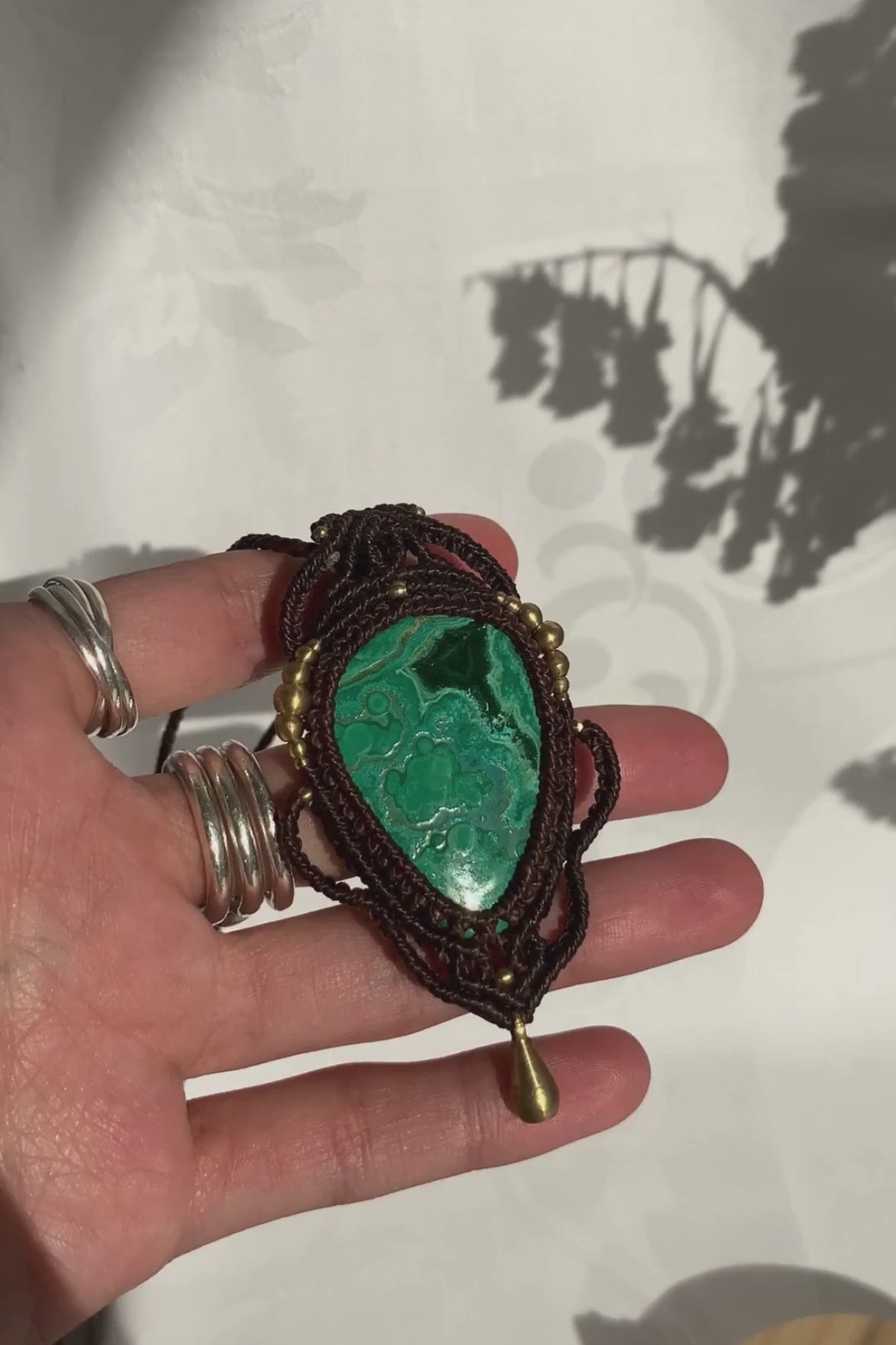 Close-up video of a handmade gemstone necklace, capturing the natural shine and intricate details of Malachite with Chrysocolla. The unique design and polished gemstones reflect the light beautifully, highlighting the craftsmanship and one-of-a-kind artistry.