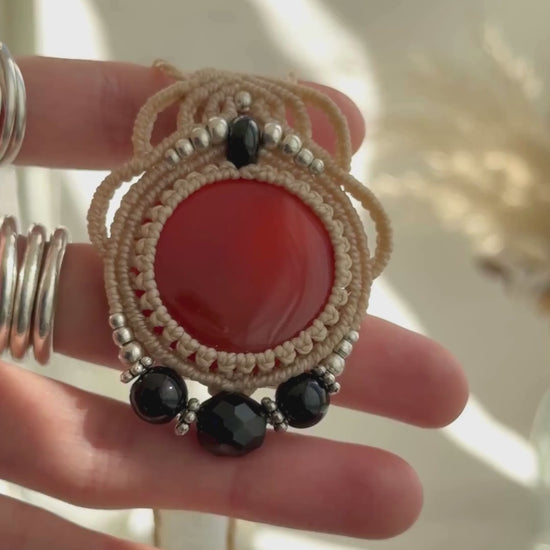 Video of a handmade Carnelian and Onyx macrame necklace. Displaying natural gemstone colors, light reflections, and fine macrame details.