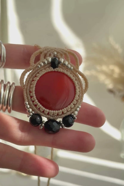 Video of a handmade Carnelian and Onyx macrame necklace. Displaying natural gemstone colors, light reflections, and fine macrame details.