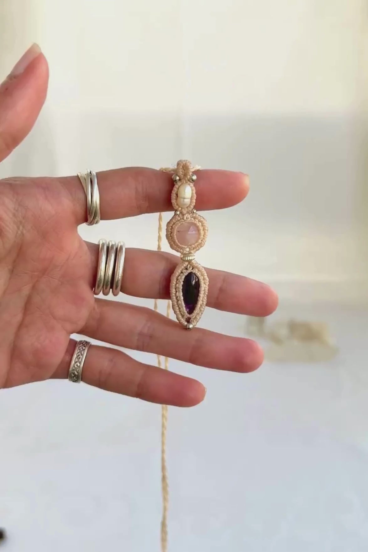 Video of a handmade Freshwater Pearl, Rose Quartz and Amethyst macrame necklace. Displaying natural gemstone colors, light reflections, and fine macrame details.