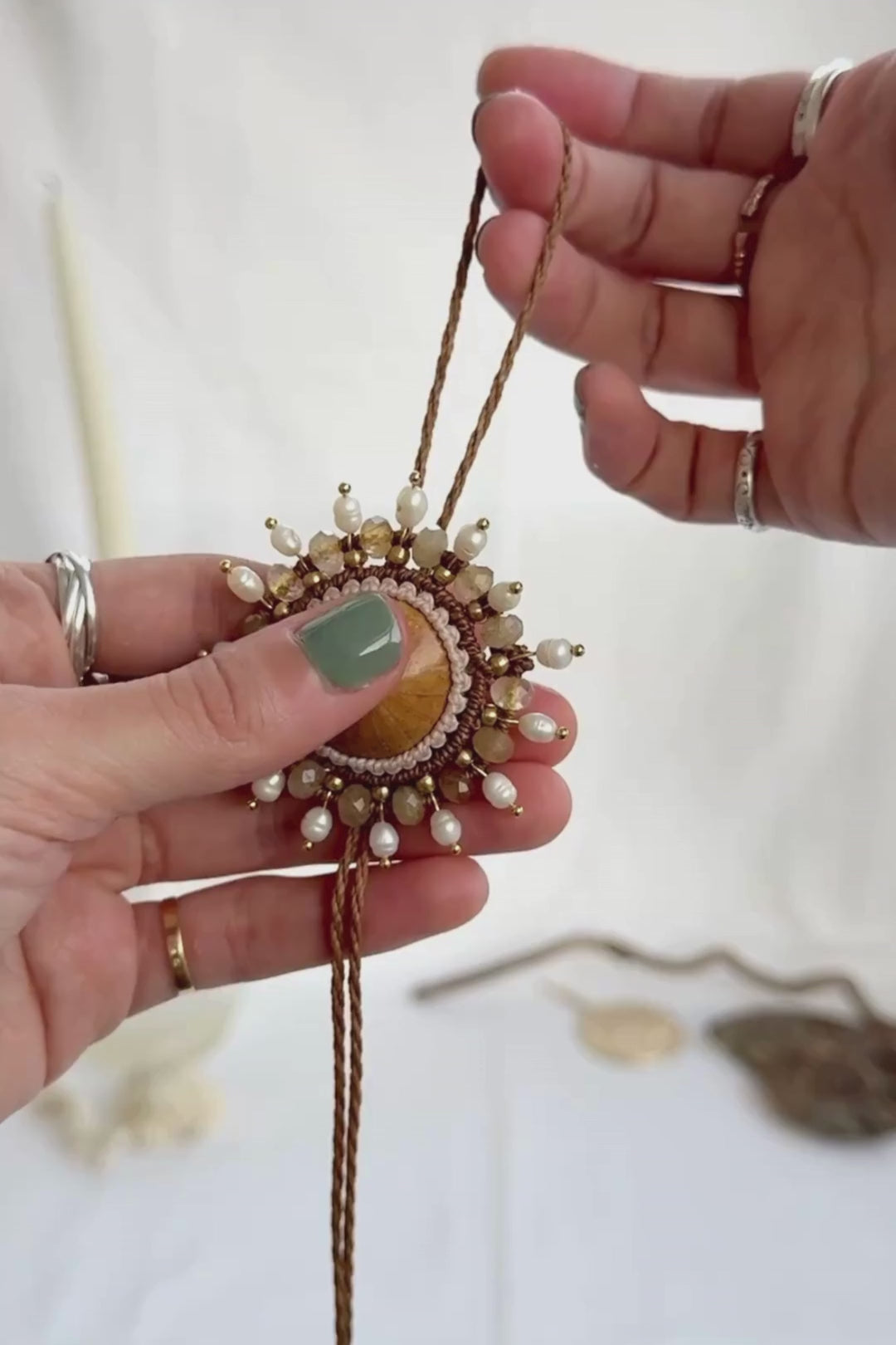Video showing sea urchin fossil bolo tie being adjusted, with close-up of centerpiece, freshwater pearls, and faceted rutilated quartz details